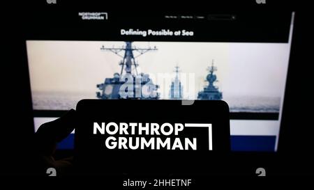 Person holding smartphone with logo of US defense company Northrop Grumman Corporation on screen in front of website. Focus on phone display. Stock Photo