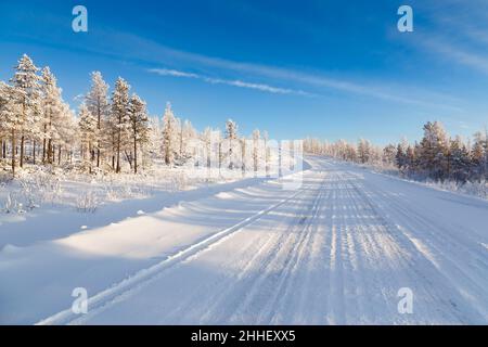 Road in the winter forest on a sunny day. South Yakutia, Russia Stock Photo