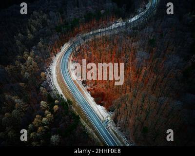 Winding road through forest, landscape with curvy highway among countryside, aerial view Stock Photo
