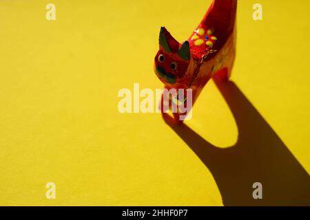 Red wooden cat figure on sunny yellow table. Stock Photo