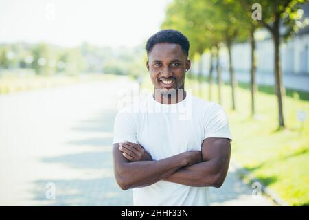 Young african american male athlete, on a morning jog, looks at the camera with his arms crossed, motivated and smiling Stock Photo