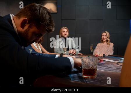 Positive people playing poker at gaming table in casino Stock Photo