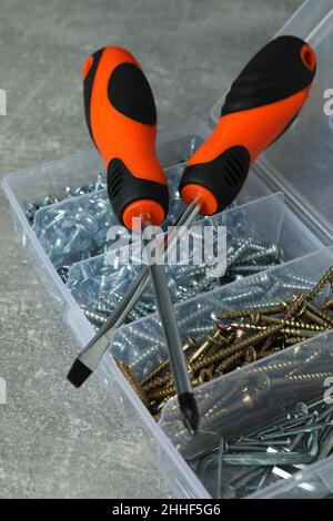Box with screws and screwdrivers on gray textured background Stock Photo