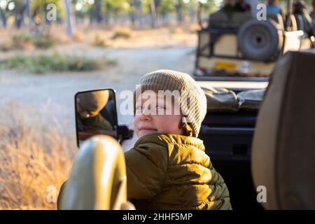 A boy sitting in a jeep on a safari drive at sunrise Stock Photo