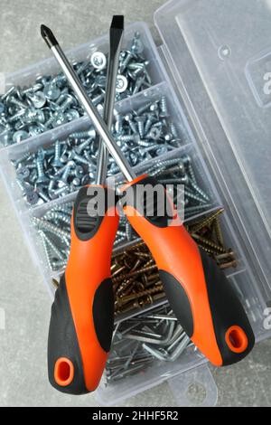 Box with screws and screwdrivers on gray textured background Stock Photo