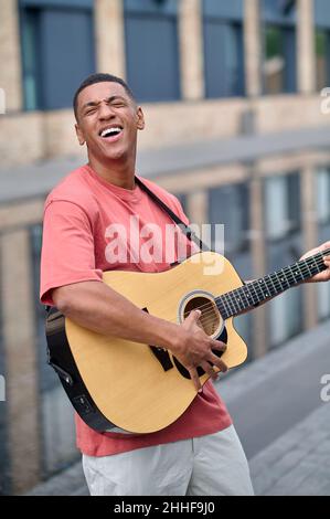 Man playing guitar with inspiration standing on street Stock Photo