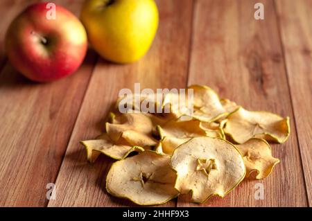 Healthy snack. Homemade dehydrated apple chips and fresh apples on a rustic wooden background Stock Photo