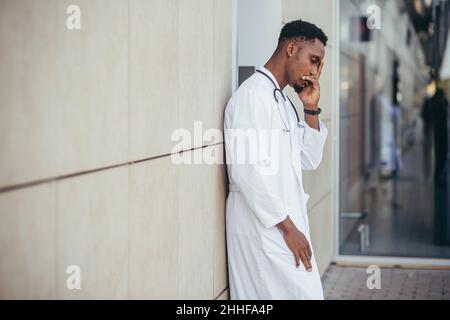 male doctor at the clinic holding his head has health problems and tired after a hard day, depressed did not get the desired result, afro american doc Stock Photo