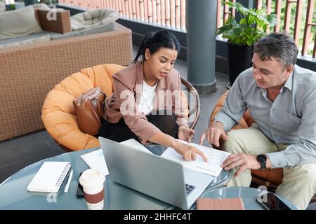 Businesswoman explaining data in sales chart to her senior colleague at meeting Stock Photo