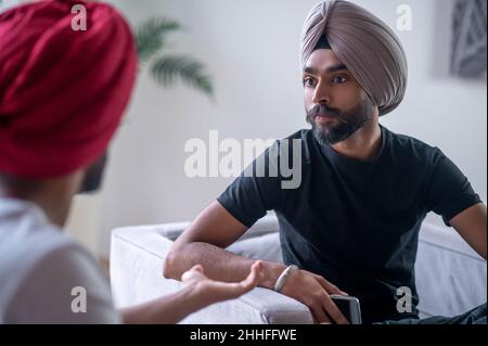Two men in turbans talking and looking involved Stock Photo