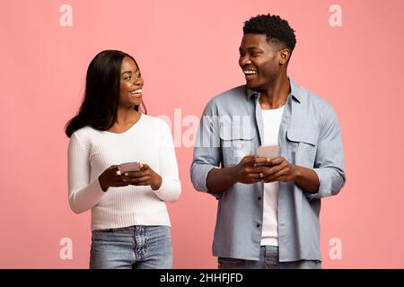 Cheerful man and woman with smartphones looking at each other Stock Photo