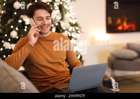Cheerful man working and talking on cellphone using pc Stock Photo