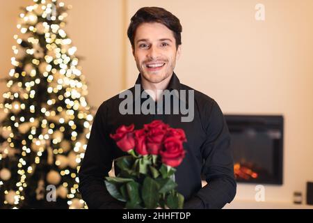 Smiling man holding roses, looking to camera Stock Photo