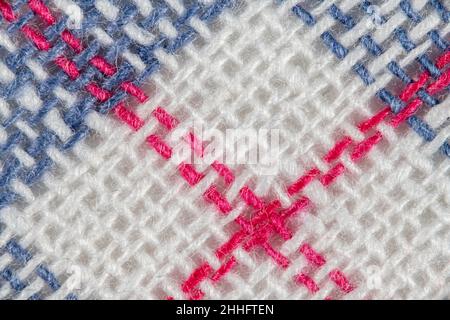 Macro close-up of 100% cotton tea towel fabric, showing cloth warp and weft thread pattern and coloured stitching. Stitched line, rows of stitches. Stock Photo