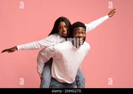 Cheerful black guy giving piggyback ride to his girlfriend Stock Photo