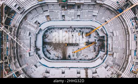 Aerial view of the construction site of a large sports stadium. Construction cranes lift loads. Stock Photo