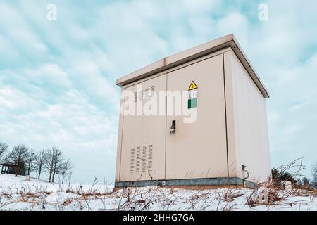 Outdoor electric high voltage distribution cabinet in a snow. Low angle view. Stock Photo
