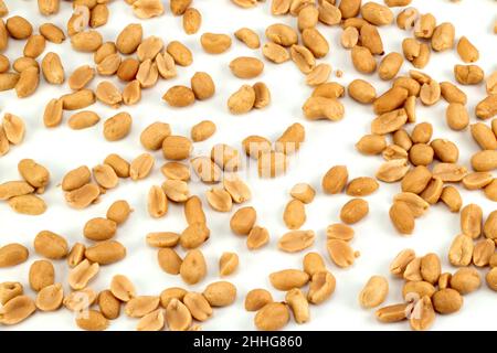 Scattered peeled salted peanuts isolated on white background. Top view. Stock Photo