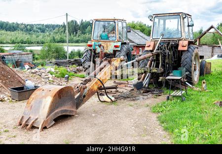 Two old rusty disassembled tractors in a Russian village in summer Stock Photo