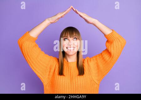 Photo of lady raise hands roof form look up empty space wear orange sweater isolated violet color background Stock Photo