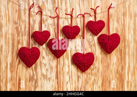 Garland of homemade hearts made from wool threads on wooden background Stock Photo