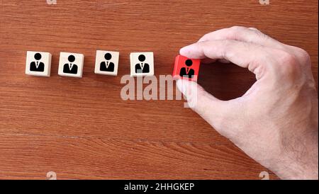 Firing, bad employee and demotion concept. Hand pick red wooden cube with employee icon Stock Photo