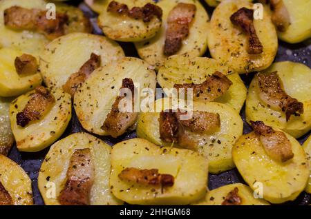 Baked potato with bacon and spices in the oven Stock Photo
