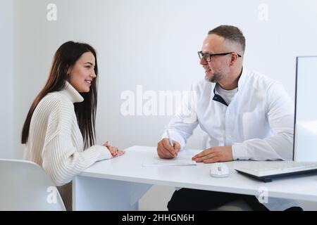 Male doctor writing a prescription for her patient. Woman at the physician office Stock Photo