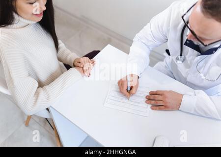 Top view of patient and doctor taking notes. The physician fills out the patient's disease card Stock Photo