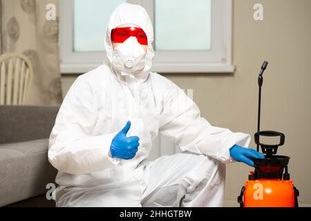 Exterminator in work clothes showing thumbs up. Fight against insects in apartments and houses. Disinsection of premises Stock Photo