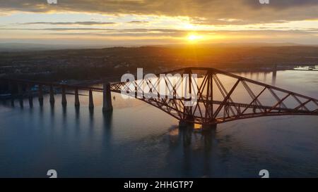 Forth Bridge , Fife, Edinburgh, Scotland, UK Weather, 24th January 2022. Sunset strikes behind the Forth Bridge which spans the Firth of the Forth Estuary. Credit: Tom McAtee/Alamy Live News Stock Photo