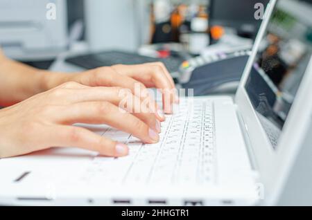 A woman is typing on a white laptop keyboard. Stock Photo