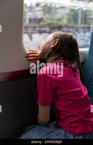Girl Êlooking through window in train Stock Photo