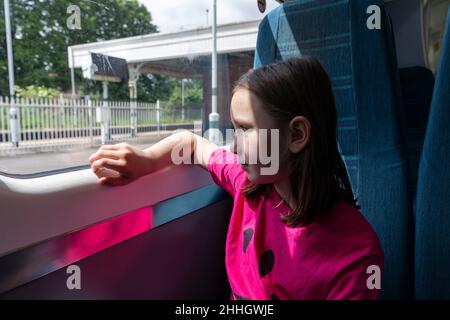 Girl Êlooking through window in train Stock Photo