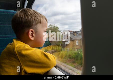 Boy Êlooking through window in train Stock Photo