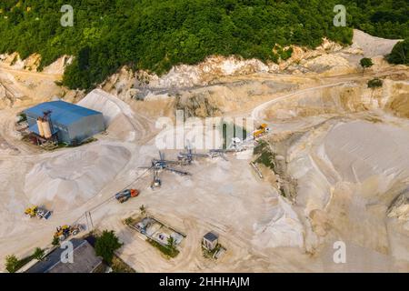 Open pit mining of construction sand stone materials with excavators and dump trucks at conveyor belt. Stock Photo