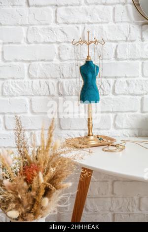 Stand with stylish jewelry on table near white brick wall Stock Photo