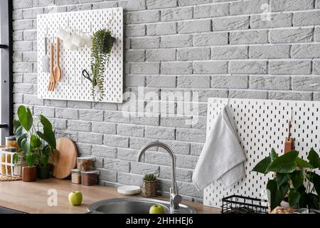 Modern counter and pegboards with kitchen utensils on grey brick wall Stock Photo