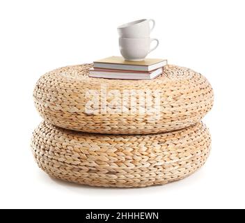 Books and cups on wicker poufs against white background Stock Photo