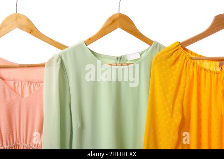 Hangers with different trendy dresses on white background, closeup Stock Photo