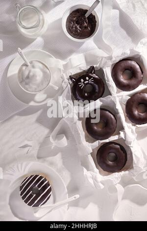 Glazed chocolate donuts and cup of cappuccino on stone background. Top view. Flat lay composition Stock Photo