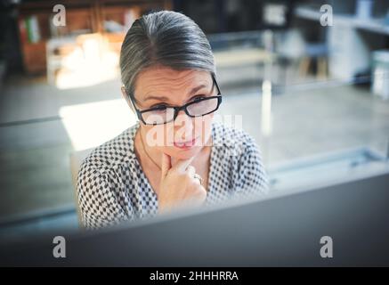 Stay focused, finish stronger. Shot of a mature businesswoman using a computer in a modern office. Stock Photo