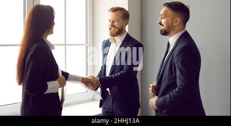 Overjoyed businesspeople shaking hands with each other getting acquainted in office. Stock Photo