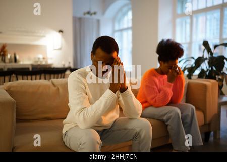 Young upset african married couple sit on sofa at home and feeling upset after quarrel Stock Photo