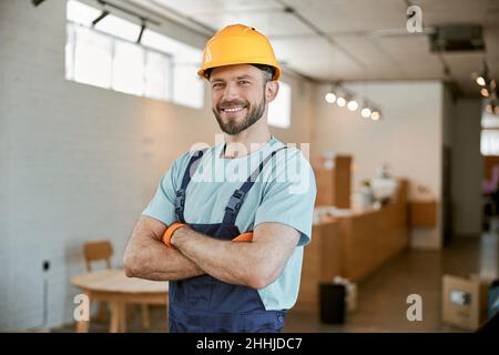 Cheerful male worker in helmet standing in workshop Stock Photo