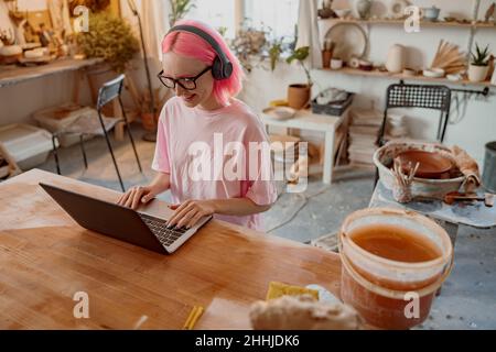 Woman potter using laptop in art studio Stock Photo