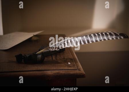 Quill pen in ink bottle on the table, close-up. Education and writing concept Stock Photo
