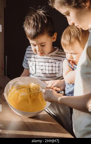 Mother teaching her son mixing dough for cake. Family having time together. Family weekend. Stock Photo