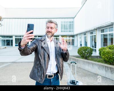 Content African American male speaking on cellphone while sitting on couch and looking away at home Stock Photo