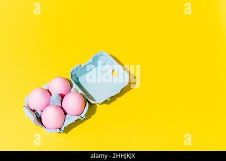 An egg cup with pink eggs on a yellow background Stock Photo